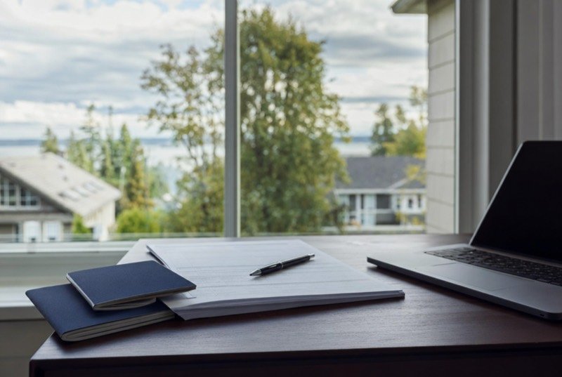 Passports, application forms and a laptop on a desk