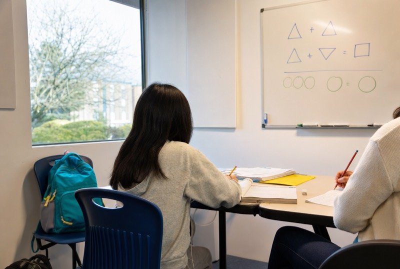 A tutoring room with a whiteboard, workbooks and a backpack