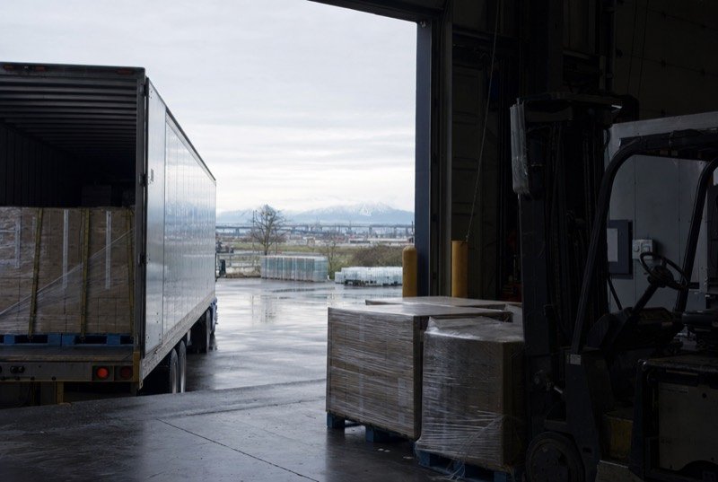 A truck at a warehouse loading dock with wrapped pallets